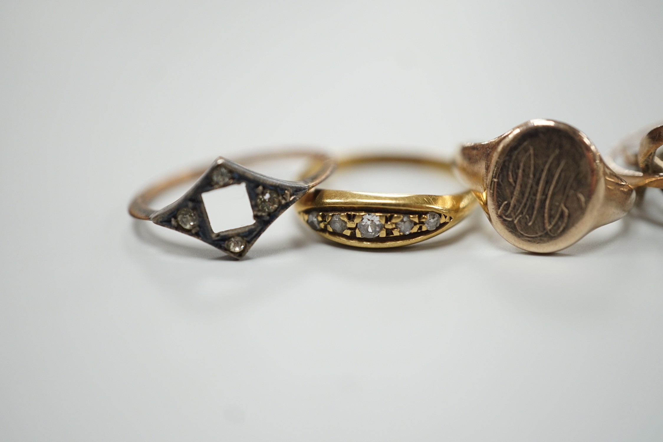 An 18ct gold and five stone diamond chip set ring, size L, gross 2.7 grams, two 9ct rings including small signet, gross 3.4 grams and a yellow metal puzzle ring.